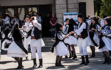 Geleneksel siyah motiflerle dikilmiş ulusal keten pastoral kostümlü Romen halk dansçıları, geleneksel siyah şapka giyen erkekler ve püsküllü siyah fular giyen kadınlar