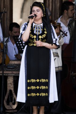 Halk sanatçıları Novaci Romanya 'da geleneksel siyah motiflerle dikilmiş keten kumaştan yapılmış ulusal pastoral kostümlerle halk müziği yapıyorlar. Erkekler geleneksel siyah şapka takıyor ve kadınlar püsküllü siyah püsküller giyiyor.