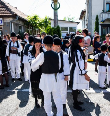 Geleneksel siyah motiflerle dikilmiş ulusal keten pastoral kostümlü Romen halk dansçıları, geleneksel siyah şapka giyen erkekler ve püsküllü siyah fular giyen kadınlar