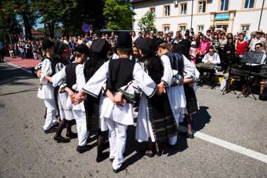 Geleneksel siyah motiflerle dikilmiş ulusal keten pastoral kostümlü Romen halk dansçıları, geleneksel siyah şapka giyen erkekler ve püsküllü siyah fular giyen kadınlar