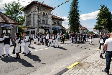 Geleneksel siyah motiflerle dikilmiş ulusal keten pastoral kostümlü Romen halk dansçıları, geleneksel siyah şapka giyen erkekler ve püsküllü siyah fular giyen kadınlar