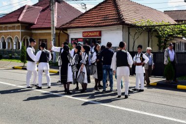 Geleneksel siyah motiflerle dikilmiş ulusal keten pastoral kostümlü Romen halk dansçıları, geleneksel siyah şapka giyen erkekler ve püsküllü siyah fular giyen kadınlar