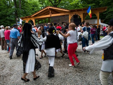 Geleneksel siyah motiflerle dikilmiş ulusal keten pastoral kostümlü Romen halk dansçıları, geleneksel siyah şapka giyen erkekler ve püsküllü siyah fular giyen kadınlar