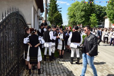 Geleneksel siyah motiflerle dikilmiş ulusal keten pastoral kostümlü Romen halk dansçıları, geleneksel siyah şapka giyen erkekler ve püsküllü siyah fular giyen kadınlar