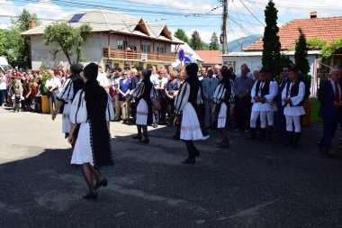Geleneksel siyah motiflerle dikilmiş ulusal keten pastoral kostümlü Romen halk dansçıları, geleneksel siyah şapka giyen erkekler ve püsküllü siyah fular giyen kadınlar