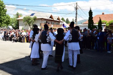 Geleneksel siyah motiflerle dikilmiş ulusal keten pastoral kostümlü Romen halk dansçıları, geleneksel siyah şapka giyen erkekler ve püsküllü siyah fular giyen kadınlar