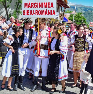 Transilvanya 'dan halk dansçıları tavus kuşu boncukları ve tüyleriyle süslenmiş astrakhan kuzu derisi şapkalar giyer, beyaz keten gömlek ve pantolon, geniş deri kemer, ulusal bayrağı temsil eden üç renkli köşegen.