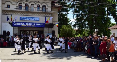 Geleneksel siyah motiflerle dikilmiş ulusal keten pastoral kostümlü Romen halk dansçıları, geleneksel siyah şapka giyen erkekler ve püsküllü siyah fular giyen kadınlar