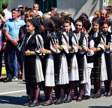 Geleneksel siyah motiflerle dikilmiş ulusal keten pastoral kostümlü Romen halk dansçıları, geleneksel siyah şapka giyen erkekler ve püsküllü siyah fular giyen kadınlar