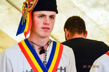 Transilvanya 'dan halk dansçıları tavus kuşu boncukları ve tüyleriyle süslenmiş astrakhan kuzu derisi şapkalar giyer, beyaz keten gömlek ve pantolon, geniş deri kemer, ulusal bayrağı temsil eden üç renkli köşegen.