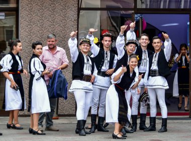 Sibiu Romania çayır çocuğu ulusal keten çoban kostümü giymiş, geleneksel siyah motiflerle dikilmiş, etek, pantolon, geniş deri kemer, göğüs ve siyah pastoral şapka ve üç renkli atkıdan oluşan bir gömlek giyiyor..