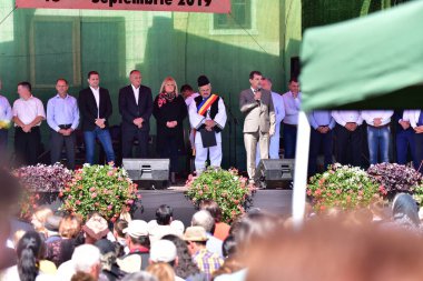 Sibiului Belediye Başkanı ve Sibiu İlçesi yetkilileri Poienari Festivali 'nin sahnesinde ve festivalin ev sahibi olarak geleneksel siyah motiflerle dikilmiş ulusal çoban keten takım elbise giyiyor.