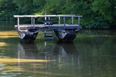 Yüzen kablo köprüsü, yükleme platformunu oluşturan kürklerle çizilmiş bir kiriş çerçevesiyle birbirine bağlı iki düz tabanlı bottan oluşur..