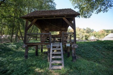 Mısır unu için el değirmeni ya da değirmeni merkezi ahşap saplı iki değirmen taşından oluşur, iki ayaklı destek çubuğu ile desteklenir, zemin seviyesinde dört tabanı vardır.