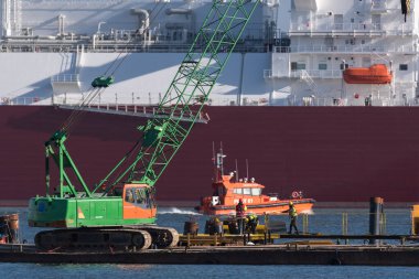 SWOUJSCIE, BATI POLAND - 2022: Arka planda bir LNG tankeri bulunan bir gaz terminali inşaatında işçiler ve inşaat makineleri 