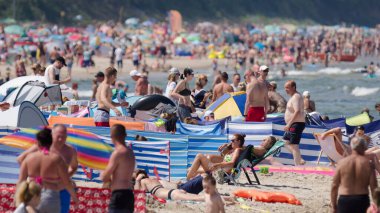 SARBINOWO, BATI POMERANYA / POLAND - 2021: Güneşli deniz plajında tatilciler yeniden yaratılıyor