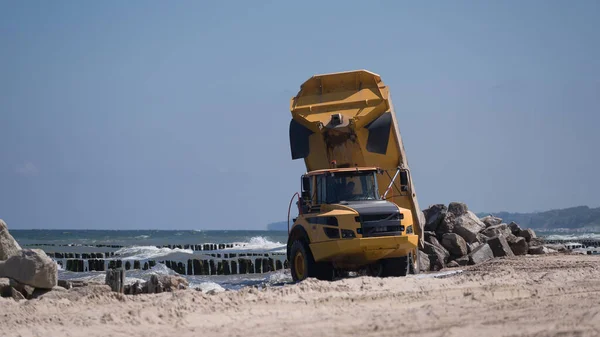 CONSTRUCTION DUMP TRUCK - A big vehicle carries boulders on the sea beach