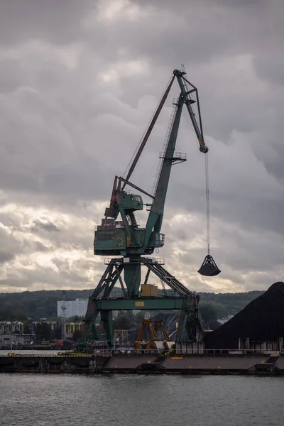 MARITIME TRANSPORT - Port crane on the quay with coal on the reloading yard