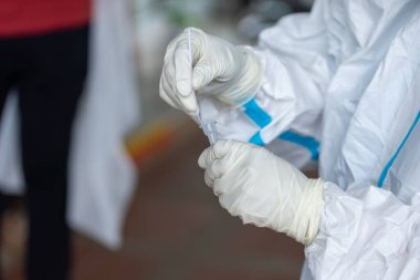 PPE giysisi olan doktor, nazal çubuk ile ATK test kiti kullanan bir test koronavirüsü (covid-19) kullanıyor..