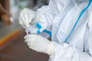 PPE giysisi olan doktor, nazal çubuk ile ATK test kiti kullanan bir test koronavirüsü (covid-19) kullanıyor..