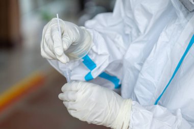 PPE giysisi olan doktor, nazal çubuk ile ATK test kiti kullanan bir test koronavirüsü (covid-19) kullanıyor..