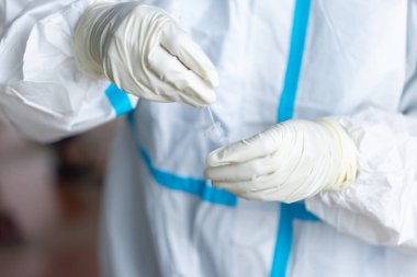 PPE giysisi olan doktor, nazal çubuk ile ATK test kiti kullanan bir test koronavirüsü (covid-19) kullanıyor..