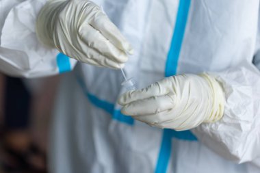 PPE giysisi olan doktor, nazal çubuk ile ATK test kiti kullanan bir test koronavirüsü (covid-19) kullanıyor..