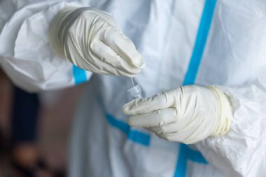 PPE giysisi olan doktor, nazal çubuk ile ATK test kiti kullanan bir test koronavirüsü (covid-19) kullanıyor..