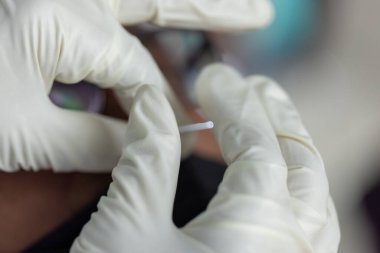 PPE giysisi olan doktor, nazal çubuk ile ATK test kiti kullanan bir test koronavirüsü (covid-19) kullanıyor..