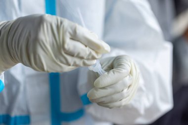 PPE giysisi olan doktor, nazal çubuk ile ATK test kiti kullanan bir test koronavirüsü (covid-19) kullanıyor..