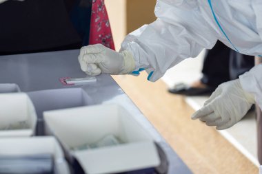 PPE giysisi olan doktor, nazal çubuk ile ATK test kiti kullanan bir test koronavirüsü (covid-19) kullanıyor..