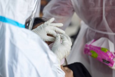 PPE giysisi olan doktor, nazal çubuk ile ATK test kiti kullanan bir test koronavirüsü (covid-19) kullanıyor..