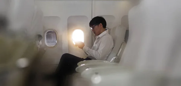 아시아인 사업가가기내 비즈니스 클래스 좌석에 행복하게 스마트폰을 사용하여 — 스톡 사진