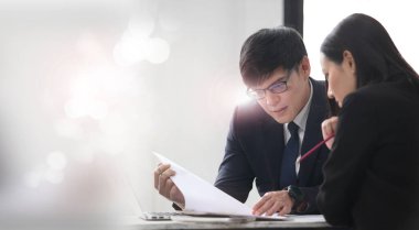 İki genç iş adamı, belediye binası geçmişine sahip ofiste çalışırken ve iletişim kurarken.