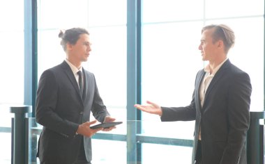 İki genç iş adamı, belediye binası geçmişine sahip ofiste çalışırken ve iletişim kurarken.