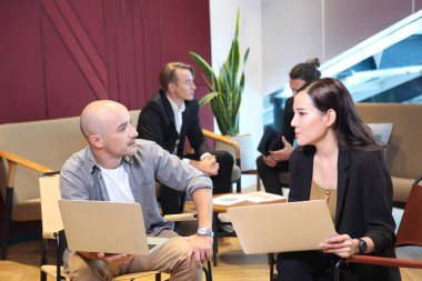 İş dünyasında çalışan ve iletişim kuran bir grup genç insan arka planda oturan meslektaşlarıyla birlikte ofis masasında oturuyorlar. Modern Ofis Toplantı Odası Yöneticileri ve Yatırımcılar Konuşuyor 