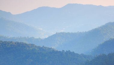 Görünür siluetlerle sabah sisli dağ sıraları. Romantik bir güneş ışığı anı.