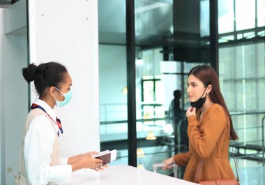 Havaalanı güvenliği, steril maskeler takarak terminal girişine giden insanların kapılarını kontrol ediyor.