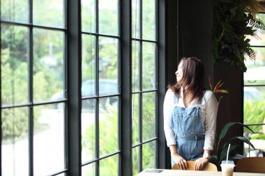 Balkonda elinde bir fincan kahve, çay ya da evinin önünde elinde kahve olan genç bir kadının manzarasıyla rahatlayan bir kadın..