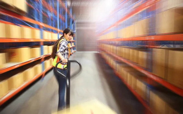 Fast Motion Blur of  Working at The Warehouse. Storehouse area, Shipment. Speeding motion of warehouse worker unloading pallet goods in warehouse storage, she using with hand pallet truck.