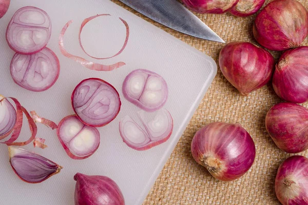 Kenevir çuvalı arka planında küçük ve büyük kesim tahtasına konmuş soğan ve bıçak. Bulanık arkaplan