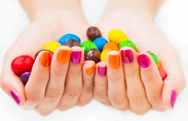 Manos de mujer sosteniendo caramelos con manicura brillante —  Fotos de Stock