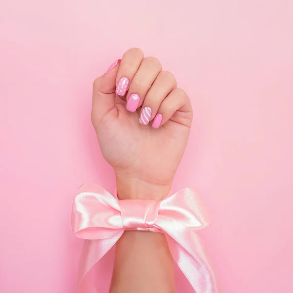 Romantik manikür tırnaklı güzel kadın elleri, pembe arka planda kalp ve sevgililer günü tasarımı.