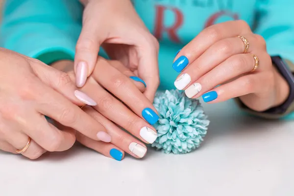 美容师手牵着女性的手 用浪漫的指甲修指甲 白色和蓝色的凝胶抛光 — 图库照片
