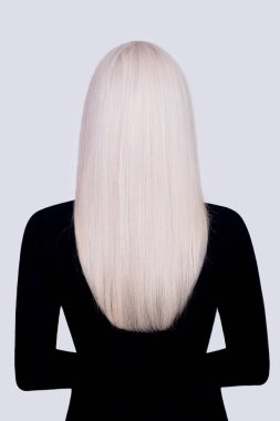 Uzun, düz, sağlıklı, sarı saçlı, siyah elbiseli, gri arka planda bir kadın.