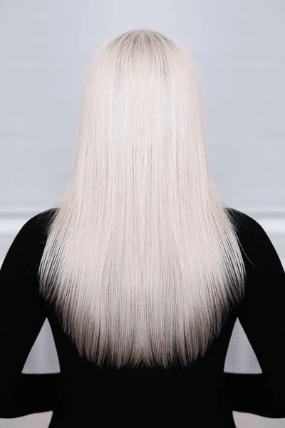 女性の背中に長く ストレートで 健康的で ブロンドの髪 黒いドレス 灰色の背景 — ストック写真