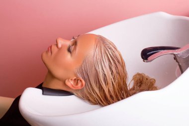 Kuaförde uzun sarı saçlı kadın saçının şampuanı.