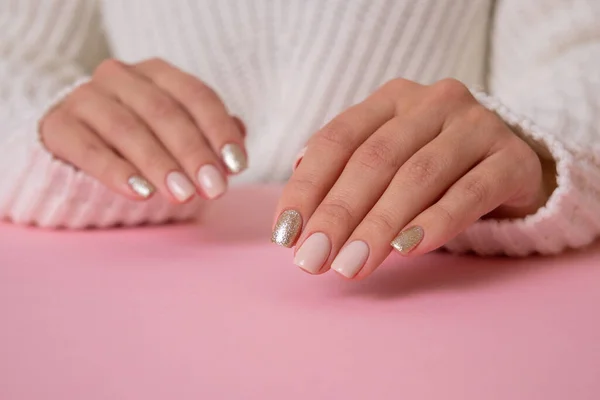 Pembe arka planda bej manikür tırnaklı güzel kadın elleri.