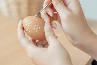 Paskalya yumurtasını beyaz boyayla boyayan genç bir kadın..