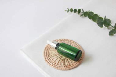 Tahta tabakta şişe serumu. Beyaz kumaş arka planında doğal yüz yağı ya da serum ambalajı. Güzellik ürünleri markası maketi. Kozmetik cilt konsepti.